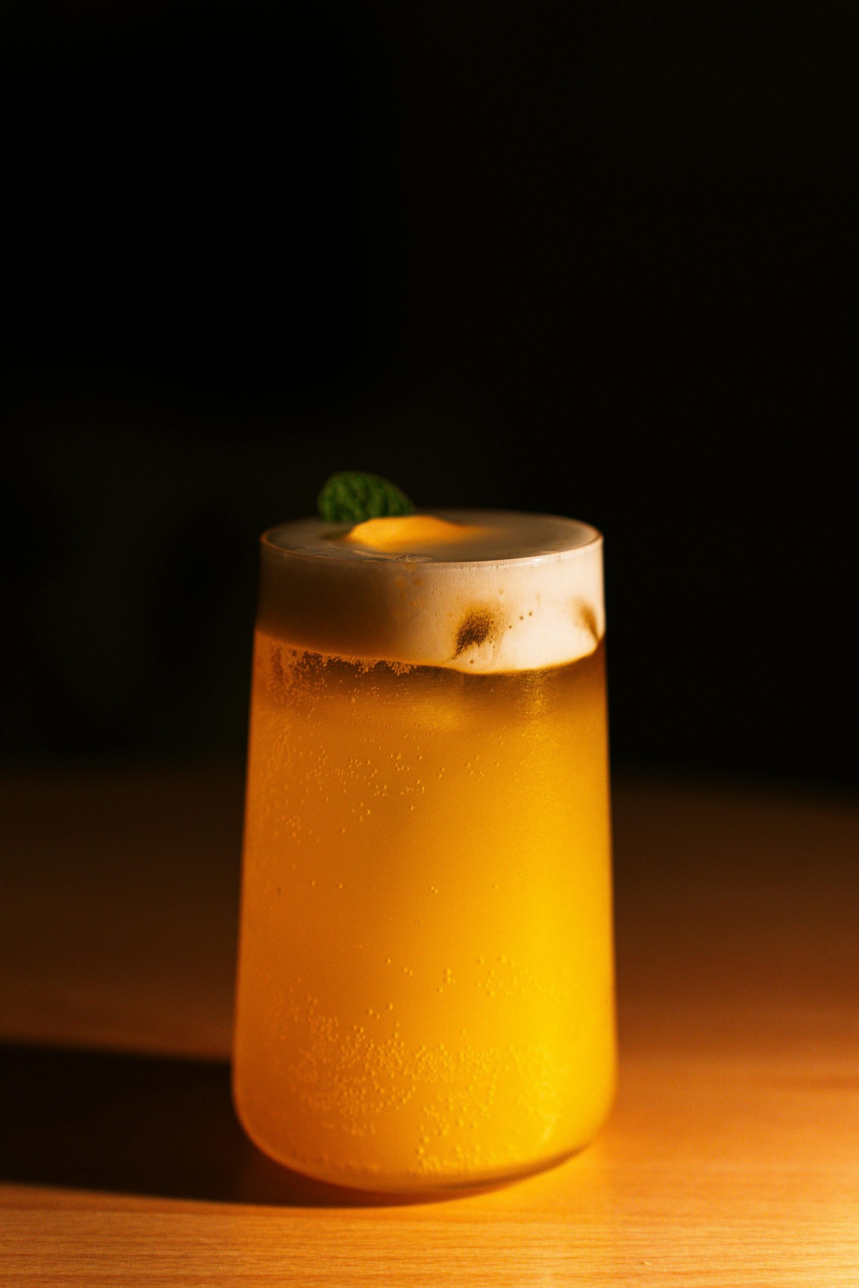 A lemon shandy beer cocktail on a wooden table in a dark room