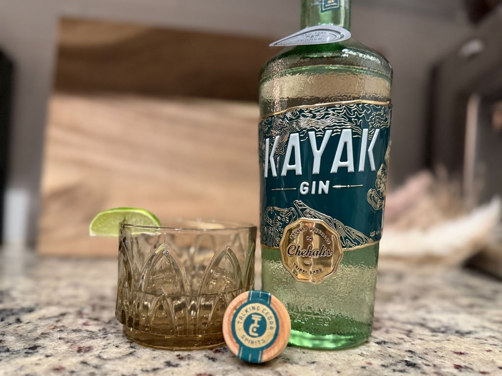A bottle of Kayak gin next to a glass with lime.
