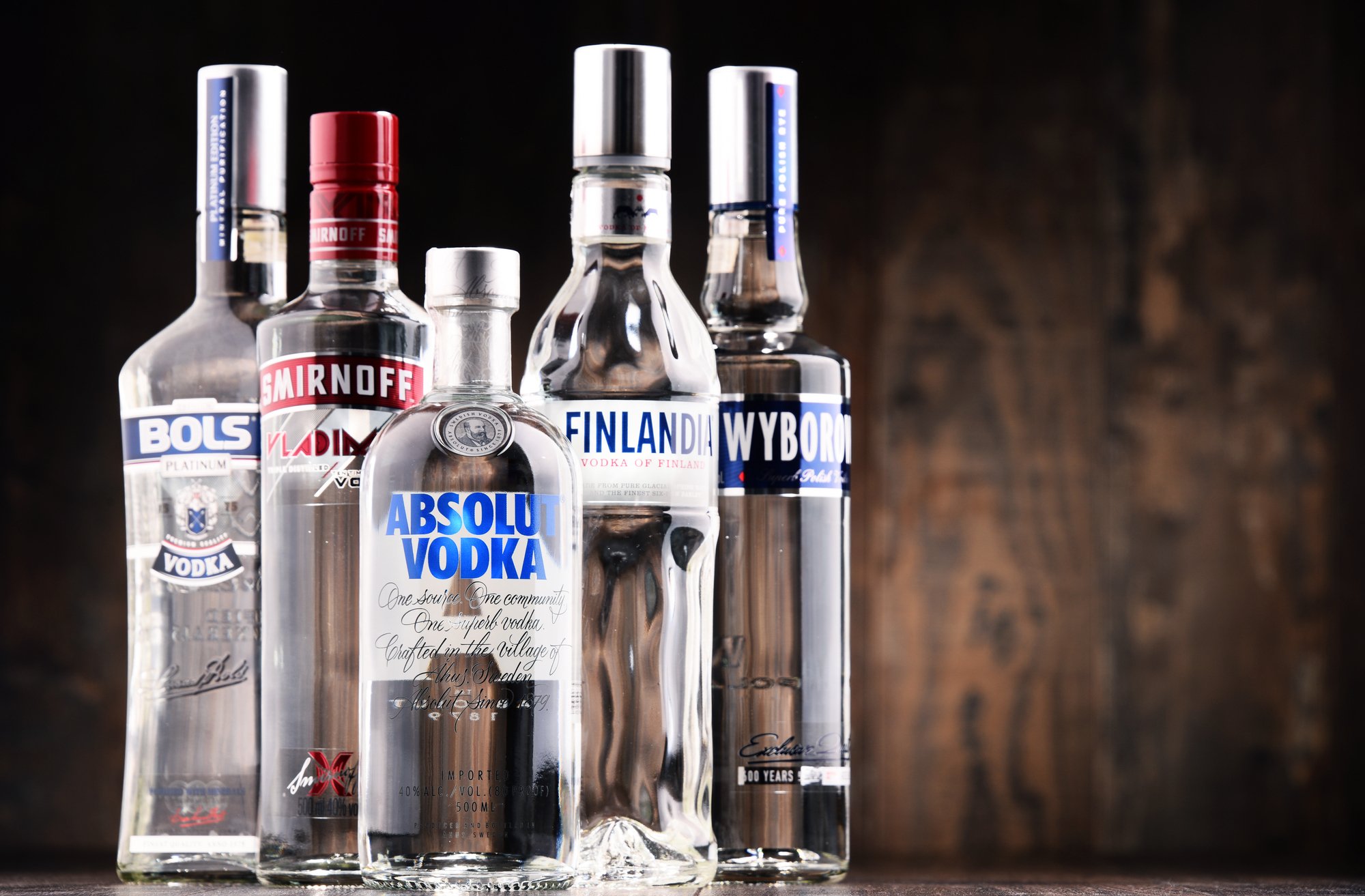 Line up of several premium vodka bottles on a wooden background