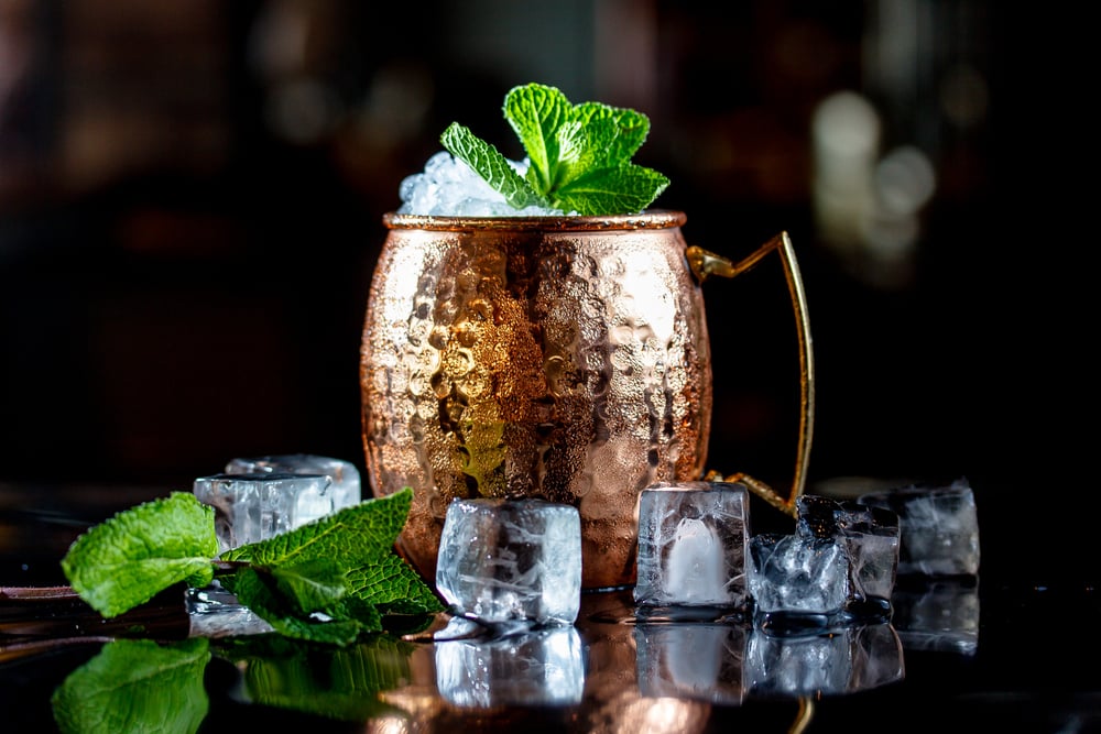 Cocktail with ice, in a copper mug on a black background.