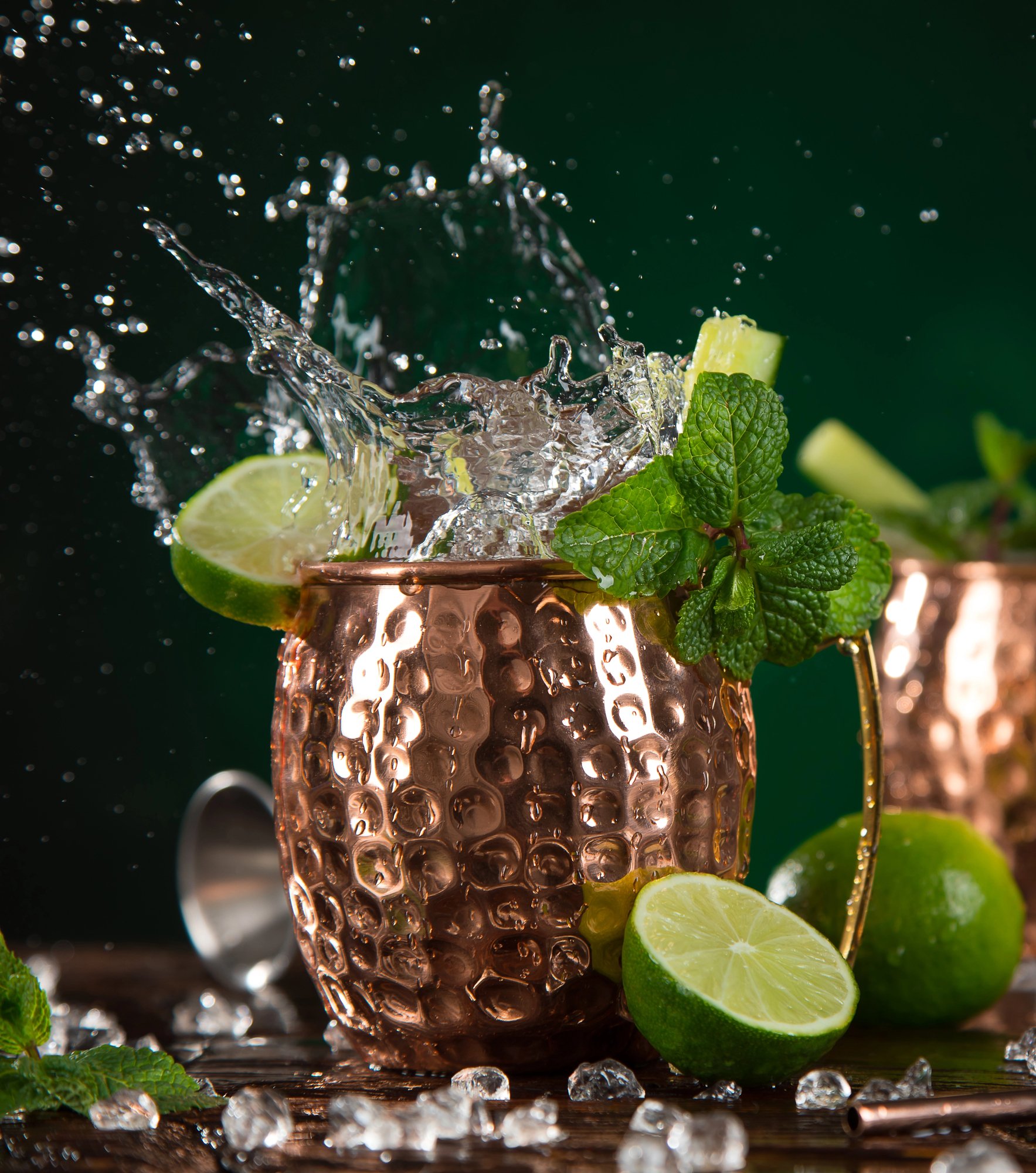 Copper mug full of Moscow Mule ingredients lime, vodka and ginger beer wth limes and mint garnish
