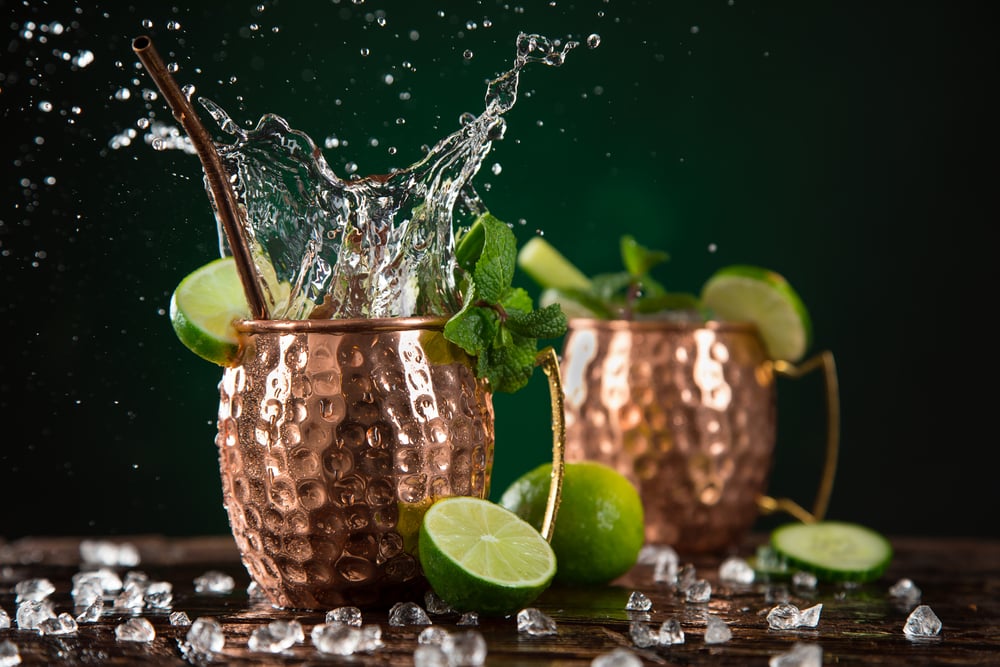 Famous splashing kentucky mule alcoholic cocktail in copper mugs, freeze motion effect.