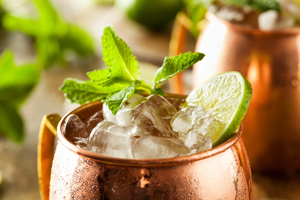 A moscow mule in a copper mug garnished with mint and lemon