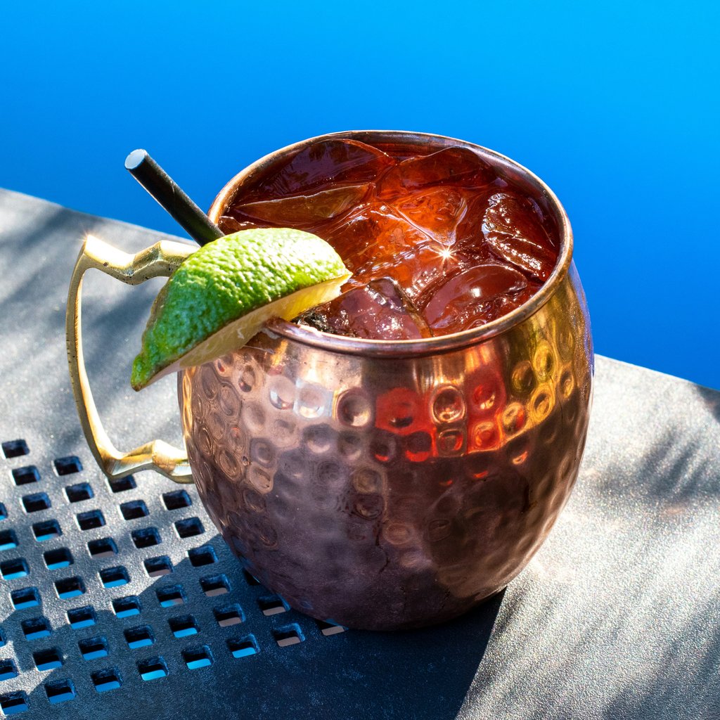 A vodka mule in a copper mug with a blue background