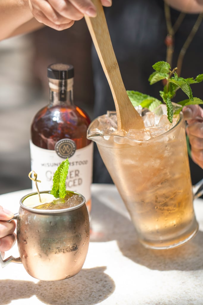 A kentucky mule in a copper mug next to a pitchr and a bottle of whiskey