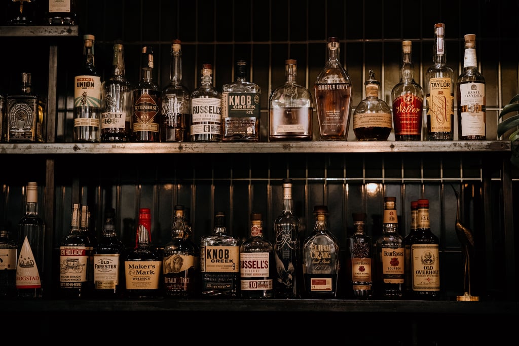 A wooden shelf full of bourbon bottles