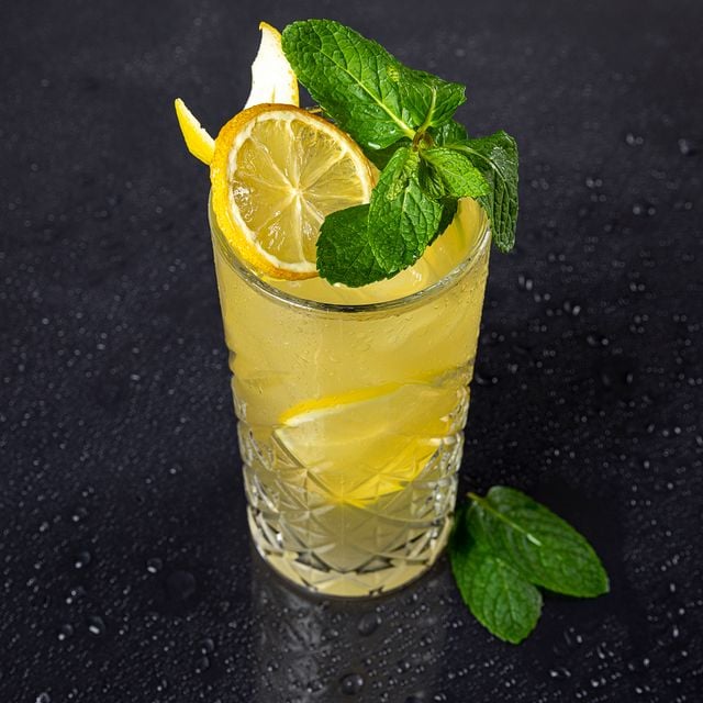 Close-up of a glass of citrusy vodka mule with mint and lemonade on a dark, surface.