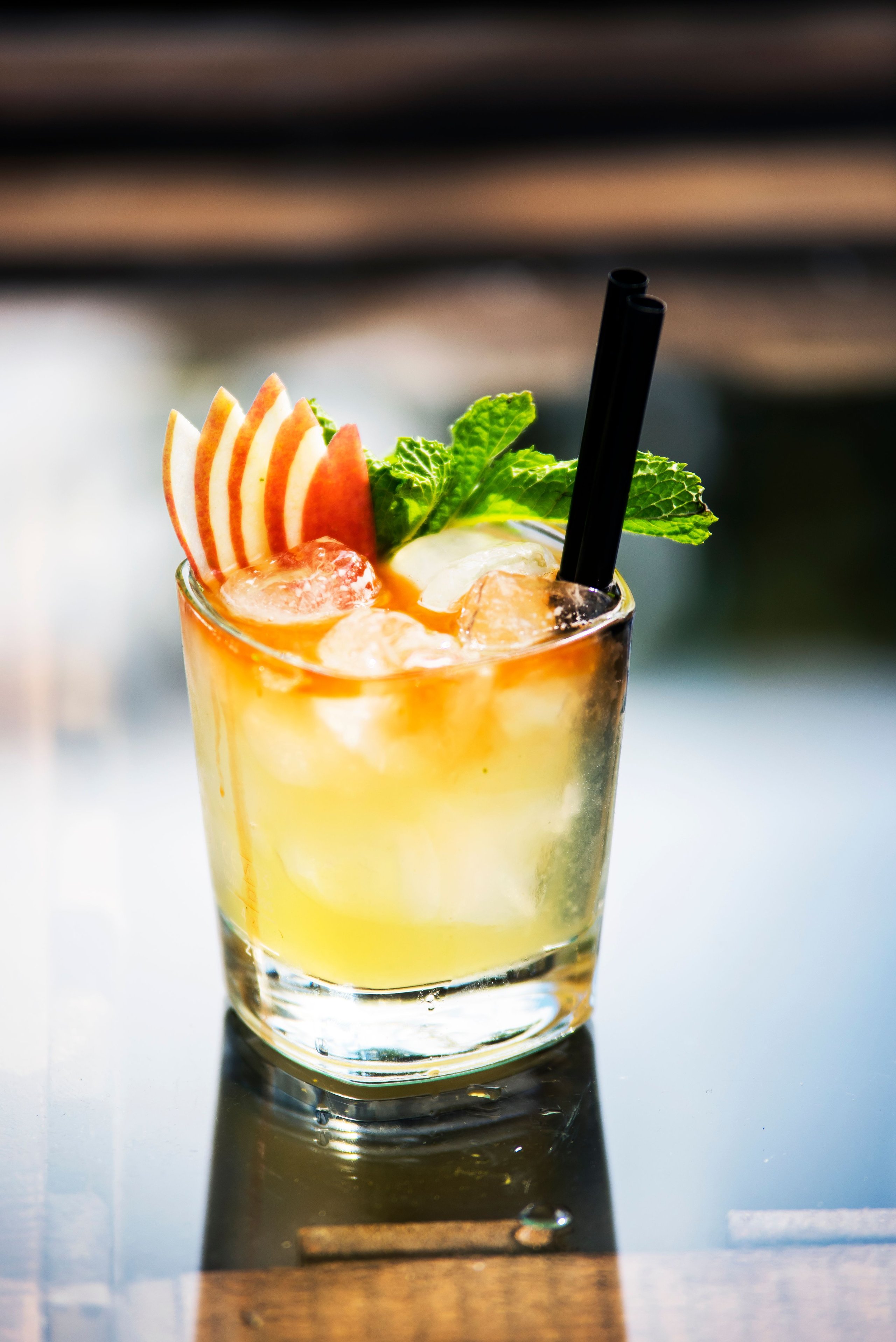A bourbon and ginger beer cocktail with apple and mint garnishes.