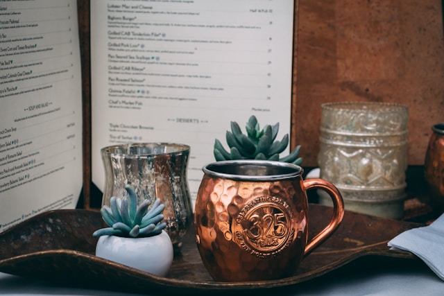 copper mule mug displayed on a restaurant table alongside decorative succulents and menu boards.
